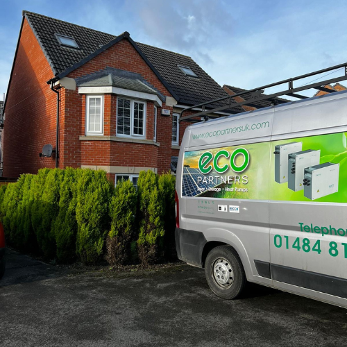 Image of the back end of a silver work van with the Eco Partners logo on the side. A red brick detached house in the background with white windows.