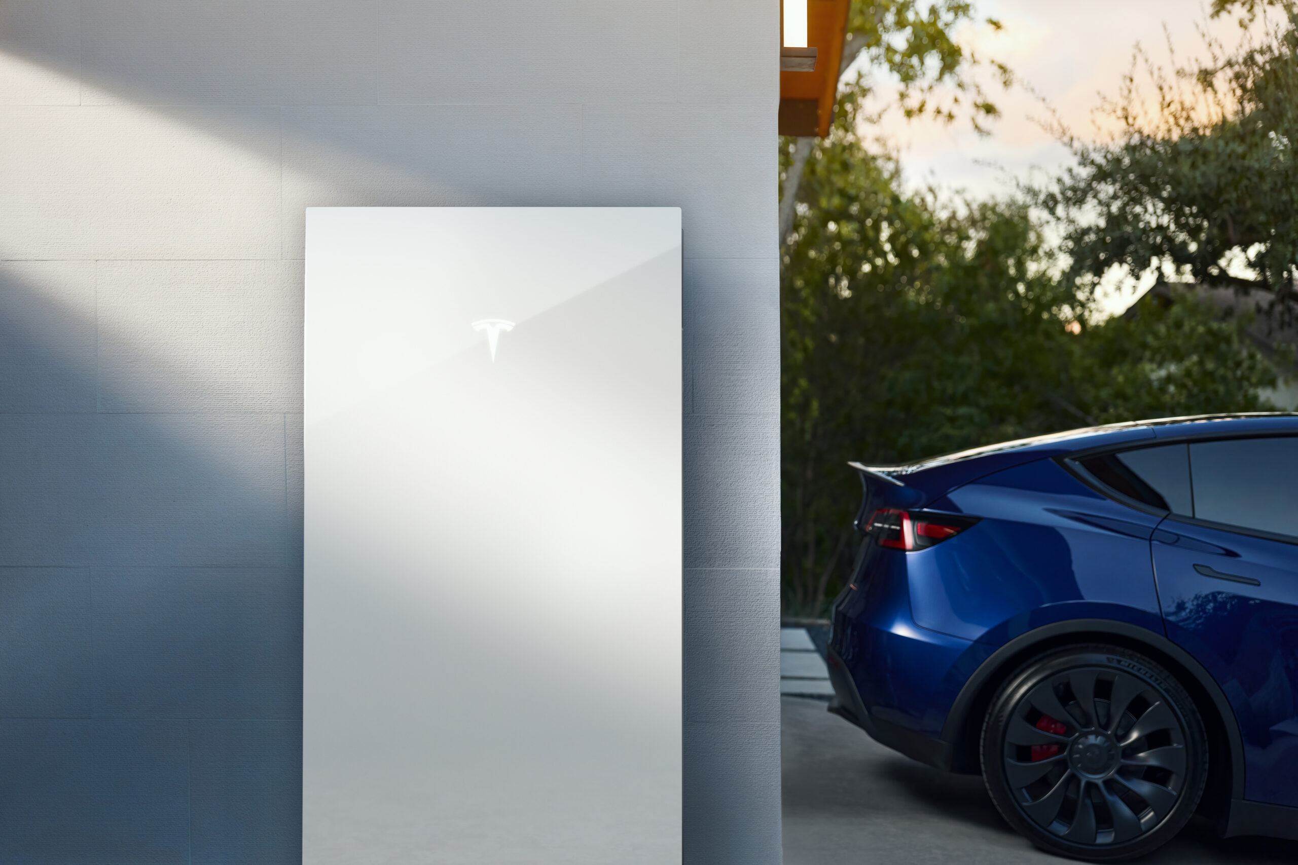 An image of a Tesla Powerwall 3 with the back end of a blue tesla car in the background.