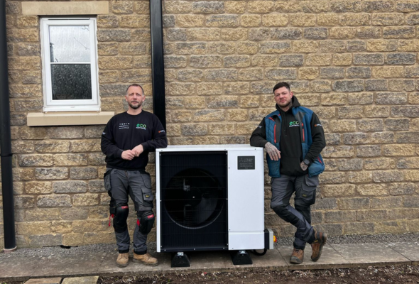 2 Eco Partners workmen stood either side of an air source heat pump