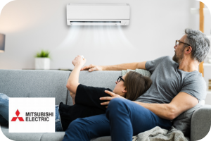 Man and women laying on a sofa pointing a remote towards a air conditioning wall mounted unit blowing out air.