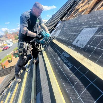 Eco Partners member of staff on a roof re-felting and laying roofing lats. Ready for new roof tiles.